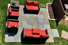 A stunning natural cleft bluestone patio featuring a unique circular stone inlay and precise rectangular patterns. Accented with white Belgian block garden edging for a clean, professional finish in Fort Washington.