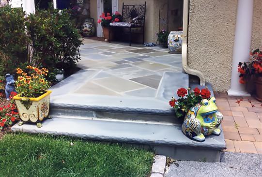 Flagstone patio with vibrant garden flowers and whimsical frog sculpture, perfect for outdoor living.