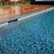 Modern swimming pool featuring grey bluestone coping with a half bullnose edge adjacent to a polished warm-toned wood deck.
