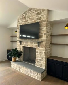 Modern stone fireplace with a bluestone hearth and mantel with mounted TV.
