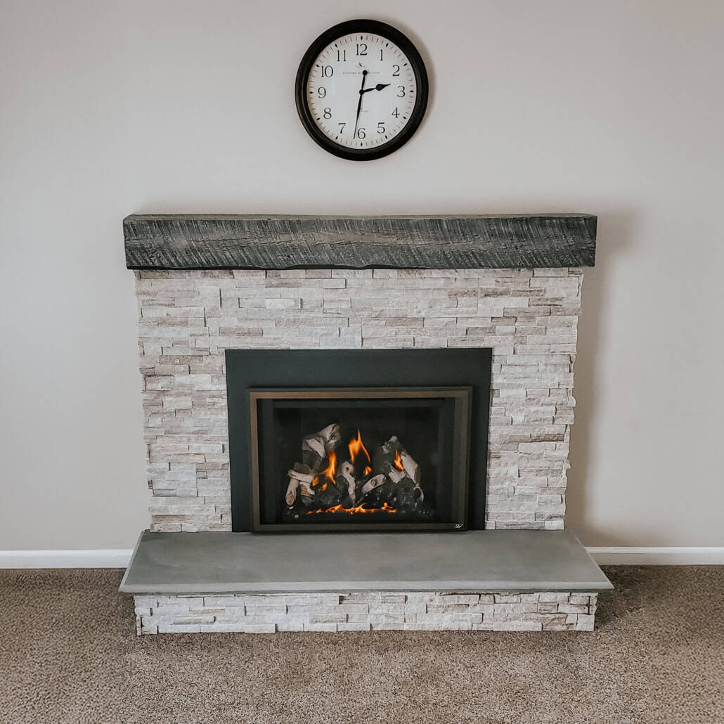 Modern stone fireplace with a smooth gray bluestone hearth and dark wooden mantel.