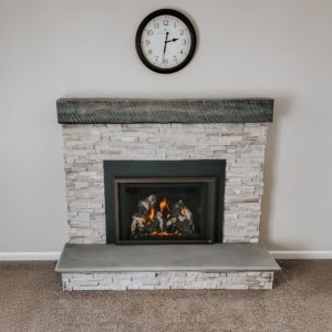 Modern stone fireplace with a smooth gray bluestone hearth and dark wooden mantel.