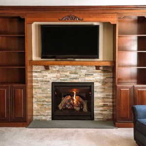 Stacked stone fireplace insert with floor-flush bluestone hearth surrounded by custom cherry built-in cabinets.